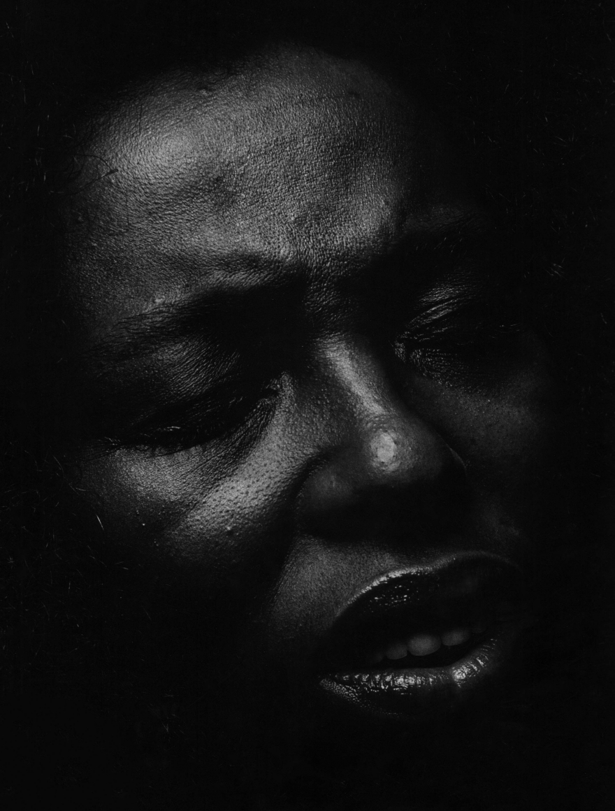 06. Anthony Barboza, Roberta Flack, singer, for Essence Magazine, ​1970s. Close up of the singer's dimly-lit face facing slightly to the right, with eyes closed and lips slightly parted.