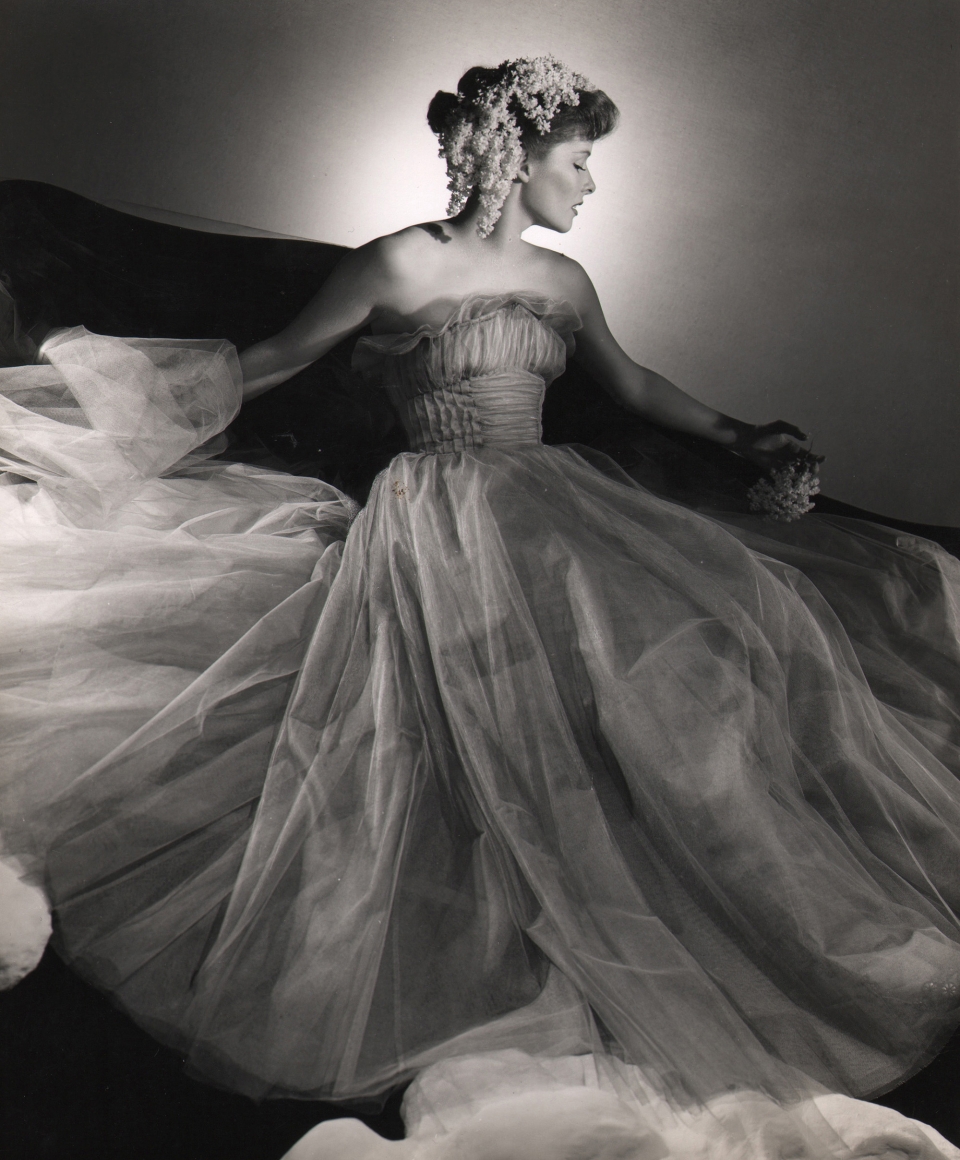 George Platt Lynes, Katharine Hepburn, ​c. 1946. Actress poses with flowing tulle gown and flowers in her hair, face turned to the right.