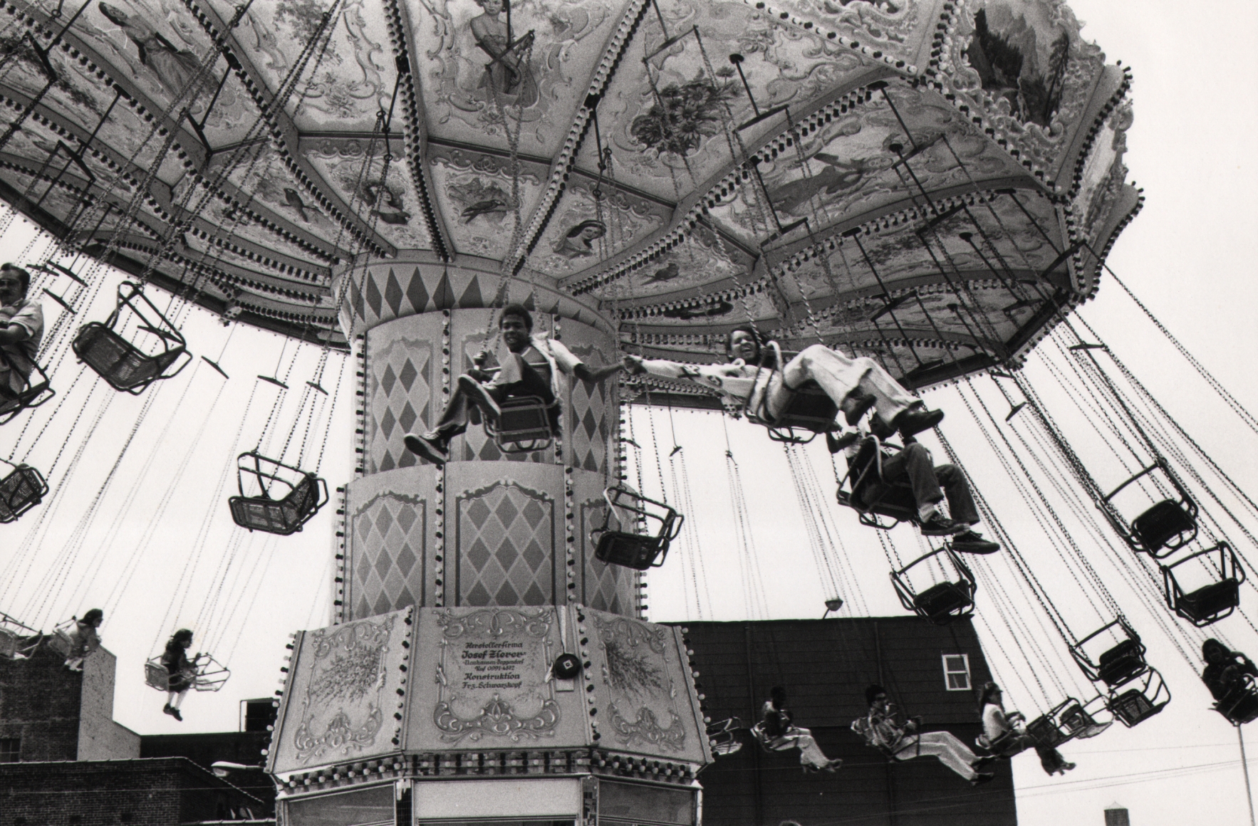 18. Anthony Barboza, Coney Island, ​1970s. A carnival swing in motion, photographed from below. The two closest riders hold hands.
