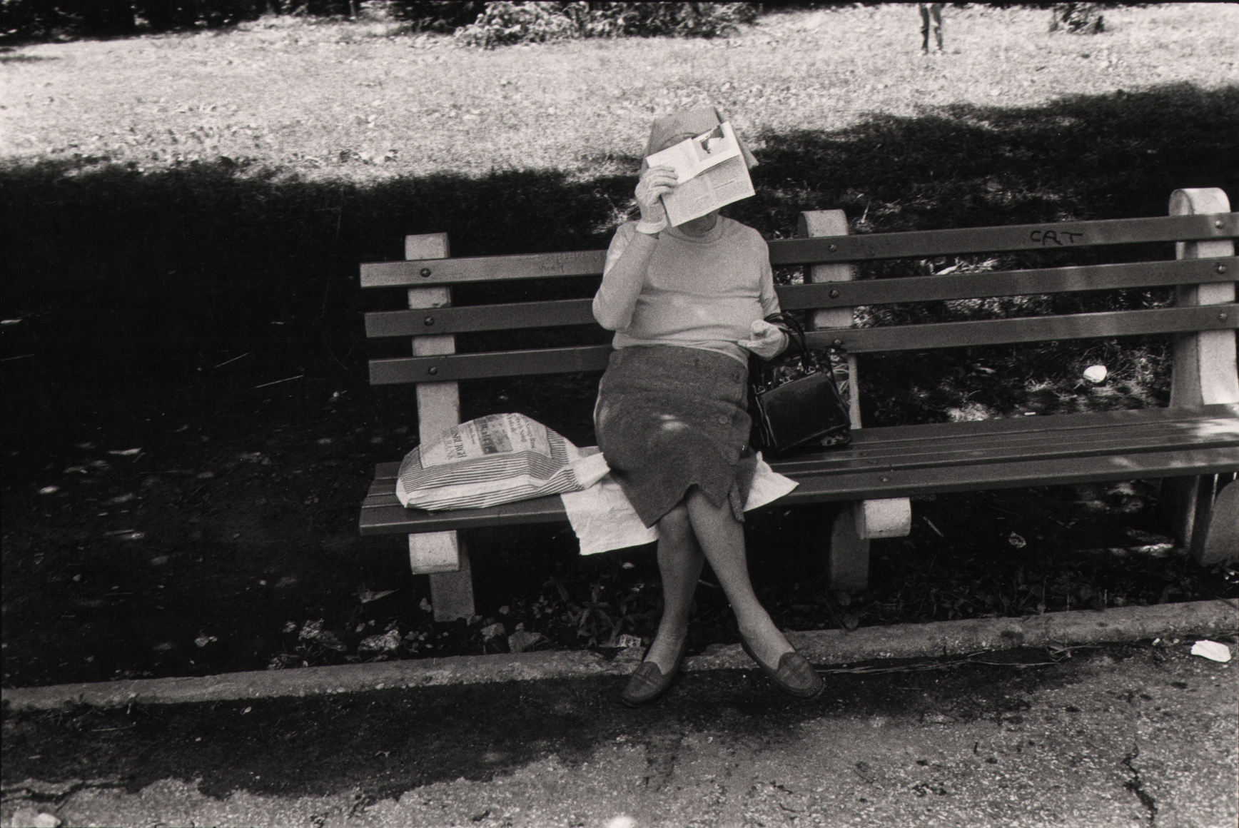 13. Anthony Barboza, Central Park, NY, ​1970s. A woman seated on a park bench holds a piece of paper to cover her face.