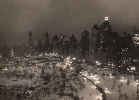 Paul J. Woolf, Central Park Looking Southeast, ​c. 1935. Night time cityscape showing the southeast corner of the park occupying the lower third of the frame with tall buildings, including "Essex House," surrounding.