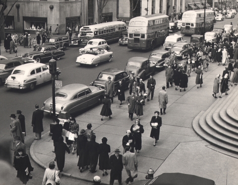 08. Simpson Kalisher, Untitled, ​c. 1949. Many pedestrians walking on a street corner from a slightly elevated view. Cars and double-decker busses can be seen on the street.
