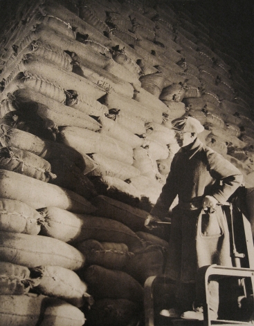Harold Haliday Costain, Edgewater, NJ Sugar Refinery, 1935. A man stands in the lower right of the frame in front of stacked sugar sacks.