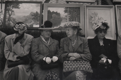 Bob Hollingsworth, Open Air Art Show, Union Square, San Francisco, ​1949. Four older women, purses in their laps, sit beneath a metal fence covered in framed landscape and still life paintings.