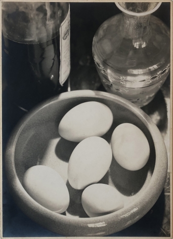 Daniel Masclet, Nature Morte, ​c. 1926. Looking down on a surface with a ceramic bowl of five eggs, a bottle of liquor, and a glass decanter.