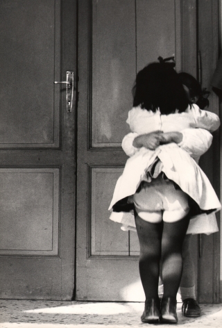 10. Renzo Tortelli, Piccolo Mondo, 1958–1959. High contrast image. Two little girls in white dresses embrace in front of a doorway.