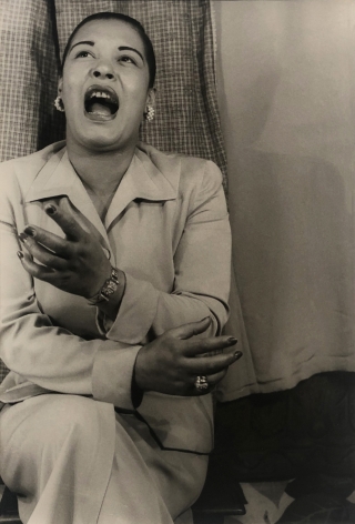 03. Carl Van Vechten, Billie Holiday, 1949. Seated portrait of the singer, eyes cast up, one hand raised, and mouth open in song.