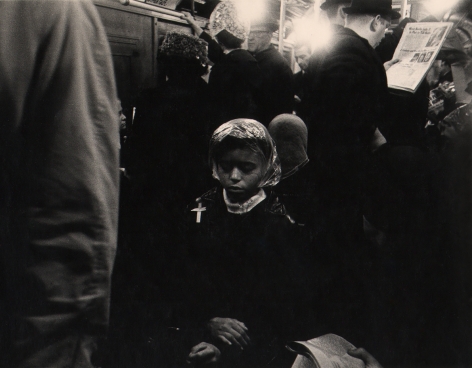 01. Beuford Smith, Palm Sunday, ​1968. A woman seated on a crowded subway, hands crossed in her lap and eyes closed.