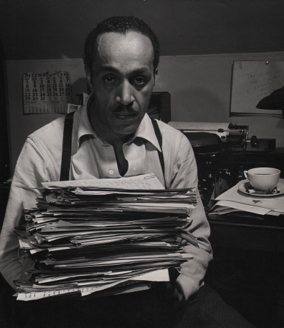 Wayne F. Miller, Willard Motley, ​1947. Subject looks into camera while holding a tall stack of papers.