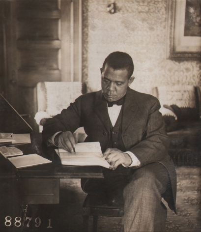 Underwood & Underwood, Booker T. Washington, ​1906. Subject is seated at a desk, writing and looking down.