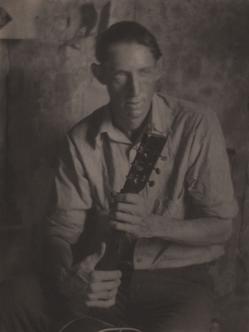 Doris Ulmann, Untitled (Guitar player), ​1928–1934. Seated man holding the neck of a guitar in both hands. His face is slightly blurred with motion.