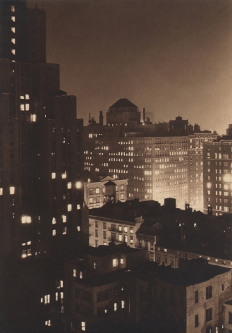 Paul J. Woolf, Untitled, ​c. 1933. Night time cityscape above and at the level of the right side buildings, with a taller building occupying the left of the frame.