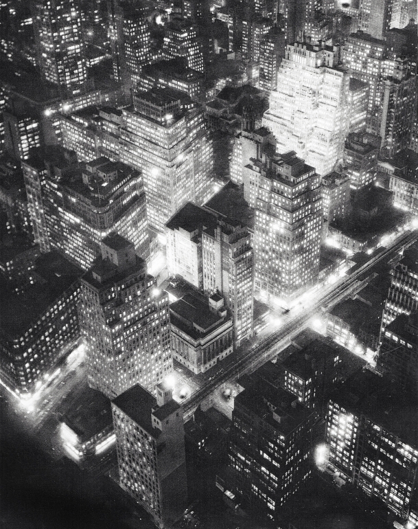 Berenice Abbott, Nightview, New York, ​c. 1932. Aerial, high-contrast night scene encompassing a few city blocks with buildings lit from inside.