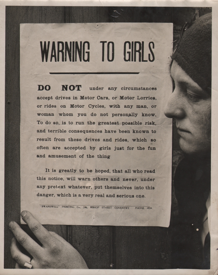 General Picture News, Churches Warning to Girls, c. 1920. A woman in profile on the right of the frame with one hand on a pasted sign that begins: "Warning to girls: Do not under any circumstances accept drives in Motor Cars, or Motor Lorries, or rides on Motor Cycles, with any man, or woman whom you do not personally know..."