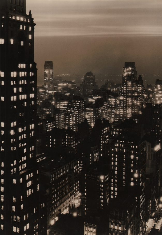 Paul J. Woolf, New York Skyline at Dusk, c. 1935. Night time cityscape with overcast sky and one building filling the left quarter of the vertical frame.